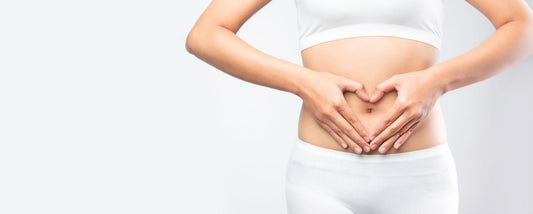 woman using hands to form a heart around her gut