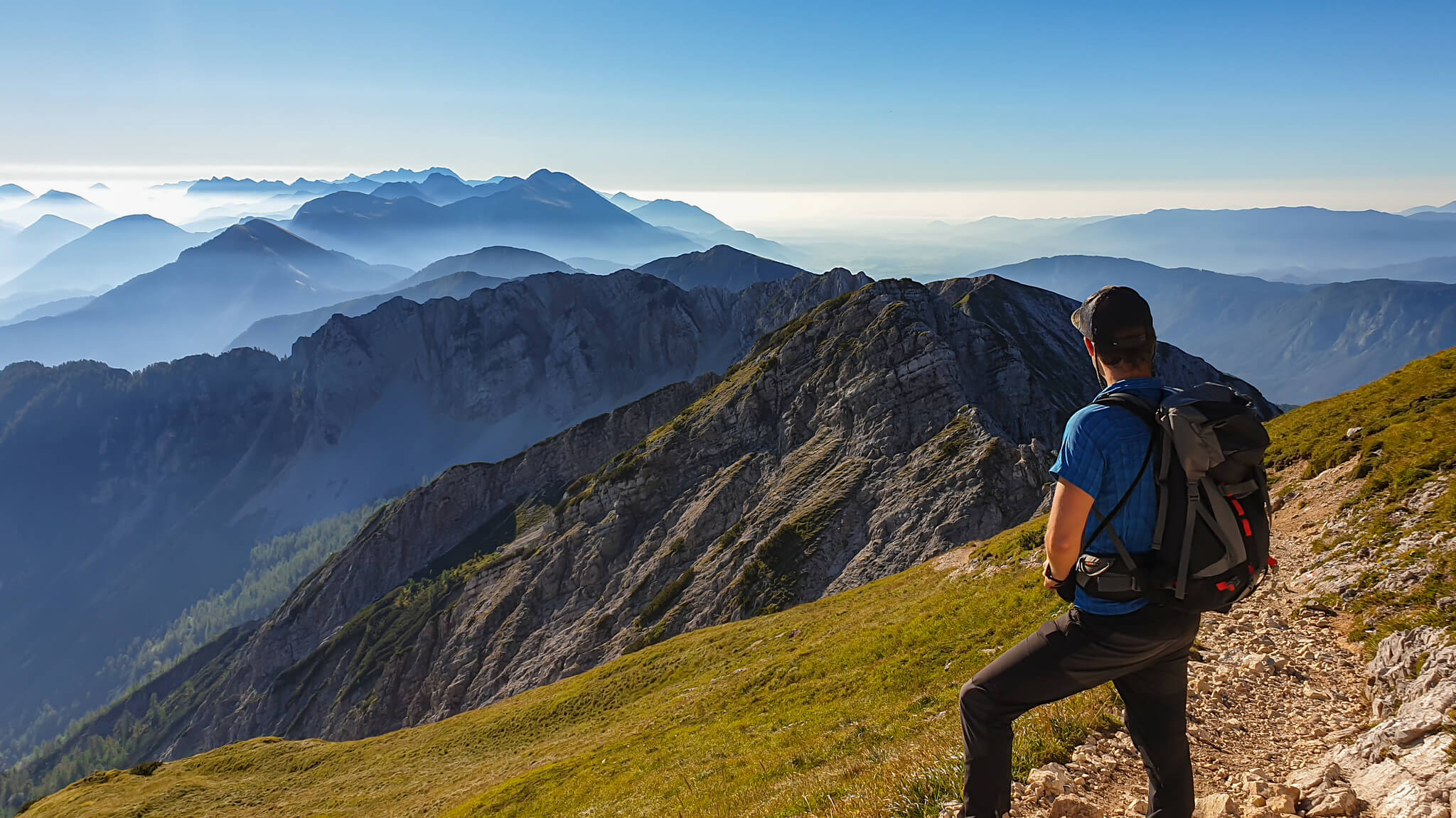 man in blue shirt with backpack hiking in mountains beautiful view