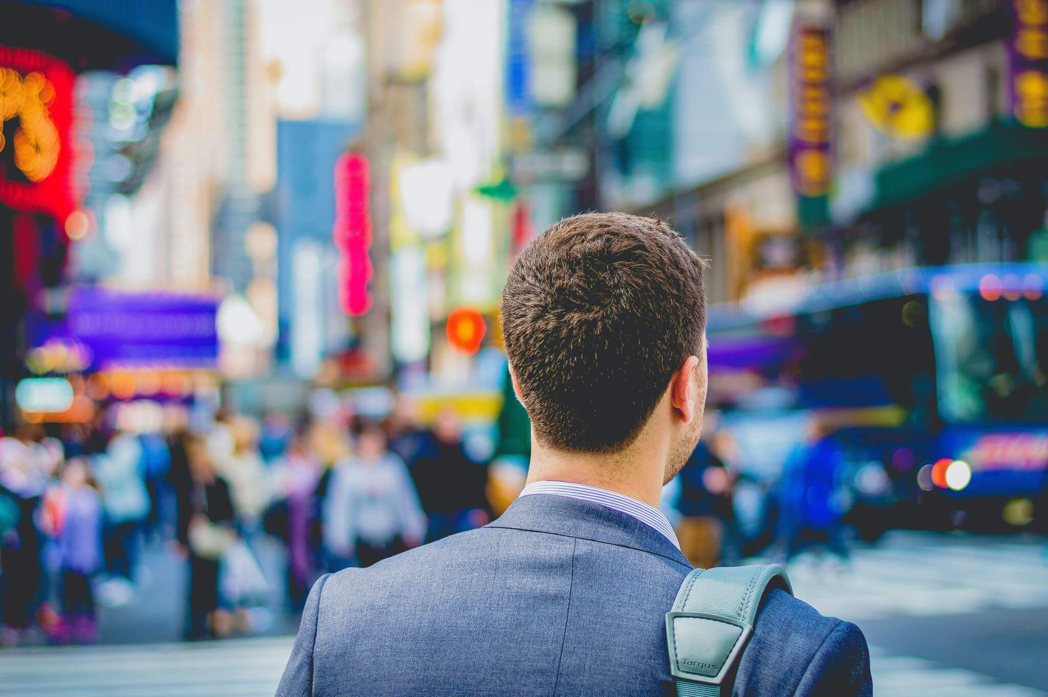 man wearing a suit in a busy city at intersection