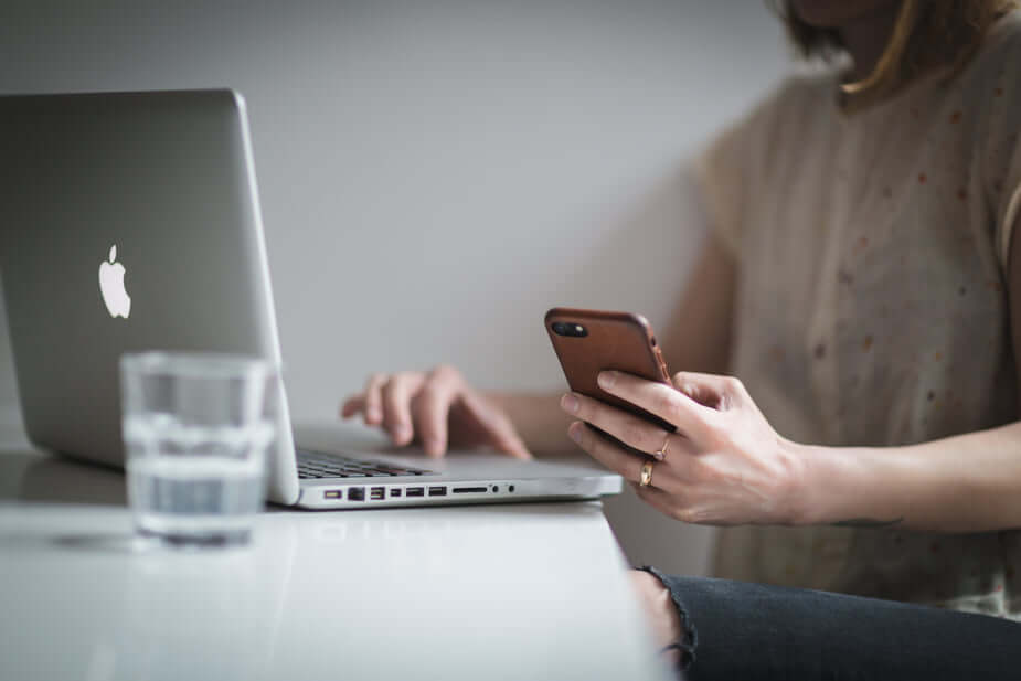 woman checking her phone while sitting at the computer