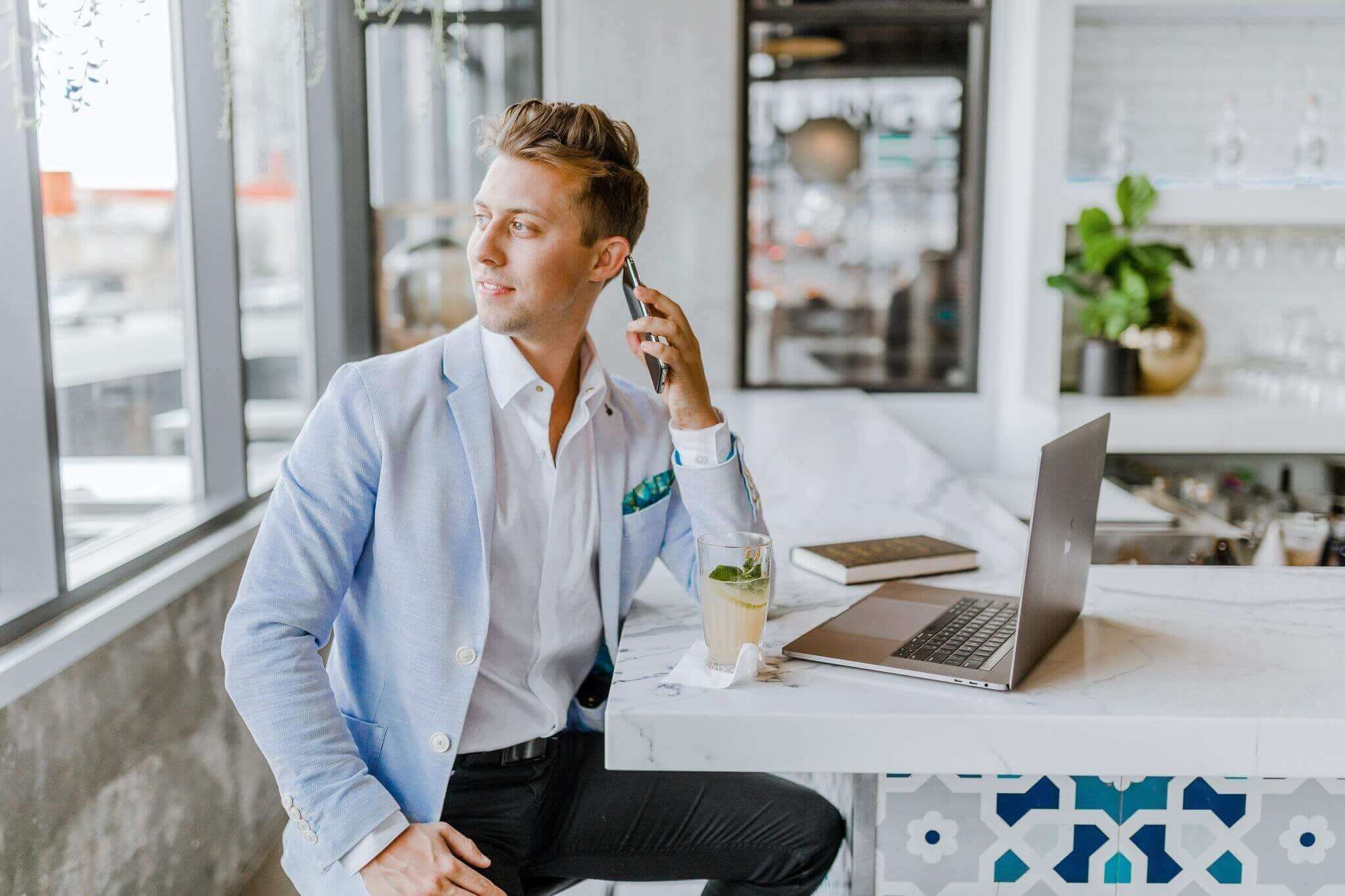 young well dressed business professional man in blue blazer on phone in restaurant looking out the window